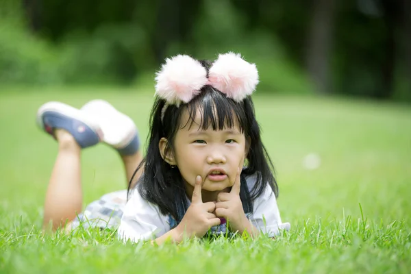 Küçük Asyalı kız parkta yeşil çimenlerin üzerinde oynama — Stok fotoğraf
