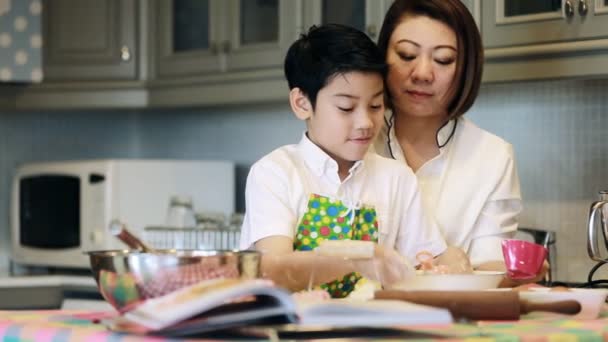 Close up a little boy toddler makes chocolate cookies with his pregnant mother . — Stock Video