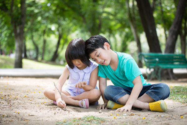 Маленький азиатский ребенок играет в песок в парке
