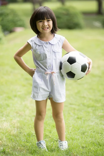 Piccola ragazza asiatica che gioca a calcio al parco — Foto Stock