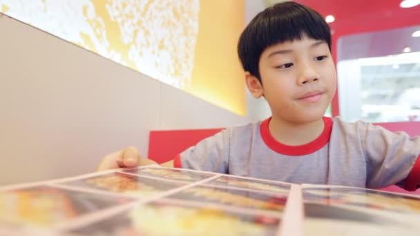 Asiático lindo chico leyendo menú libro y punto. Cara feliz — Vídeo de stock