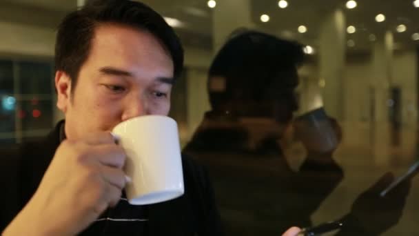 Hombre de negocios asiático utilizando en el teléfono móvil y el uso de teléfono inteligente en la noche en la cafetería. Hombre guapo esperando a alguien, Bangkok Tailandia — Vídeos de Stock