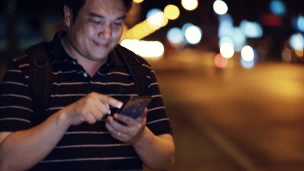 Telefoon 's nachts in de stad. Knappe toeristische man wachten iemand, Bangkok Thailand. — Stockvideo