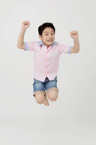 Szczęśliwy azjatycki chłopiec skacze w studio. — Zdjęcie stockowe