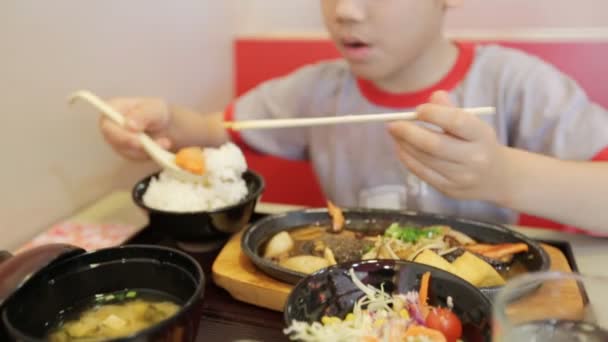 Szczęśliwy dziecko azjatyckie jedzenie sushi w restauracji z twarzy uśmiech — Wideo stockowe