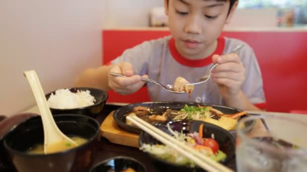Щаслива азіатська дитина їсть суші в ресторані з посмішкою обличчя — стокове відео