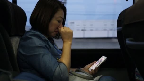 Νεαρή γυναίκα της Ασίας χρησιμοποιώντας smartphone οδηγώντας το λεωφορείο — Αρχείο Βίντεο