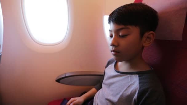 Азиатский мальчик пристегивает ремень безопасности в самолете — стоковое видео
