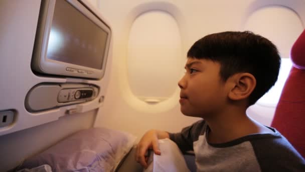 Junge asiatische Kind entspannen gerade Film im Flugzeug. — Stockvideo