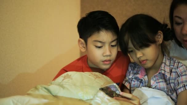 Feliz família asiática se divertindo enquanto joga jogo no telefone inteligente na cama, no quarto  . — Vídeo de Stock