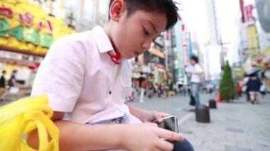 Tokyo, Japonya, street yürüyüş yakınındaki akıllı cep telefonu kullanarak mutlu Asyalı çocuk