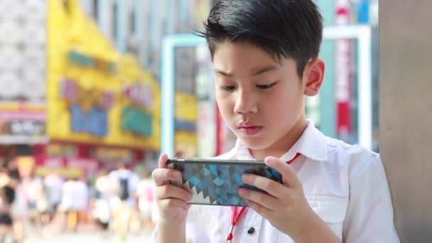 Щасливі азіатських хлопчик за допомогою смарт-мобільний телефон поблизу ходьба вулиці в Токіо, Японія — стокове відео