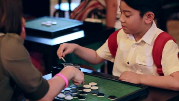 Happy asiatiska pojke spelar brädspel med hans mor, leende ansikte — Stockvideo