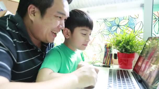 Happy Asian father and son are browsing the internet on laptop computer . — Stock Video