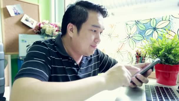 모바일에서 얘기 하는 동안 노트북을 사용 하 여 아시아 사업가의 샷 — 비디오