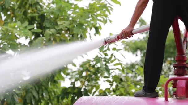 Neidentifikovaný asijské pracovník pomocí silné hadici rozprašovače z cisterny na mytí silnice — Stock video