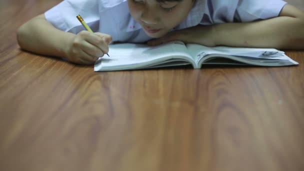 Aziatische schattige jongen leest het boek op de verdieping thuis. — Stockvideo