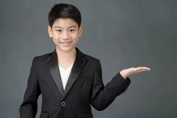 Liten asiatisk pojke pekar till utrymme till höger med handflatan uppåt — Stockfoto