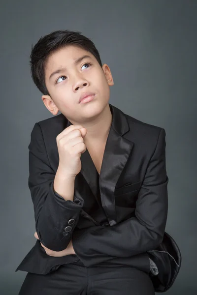 Liten asiatisk pojke i svart kostym upprörd, depression ansikte — Stockfoto