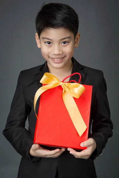 Portrait of asian boy in black suit holding gift bag — Stock Photo, Image