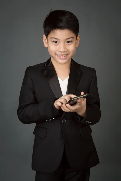 Feliz asiático niño en negro traje celebración digital celular —  Fotos de Stock