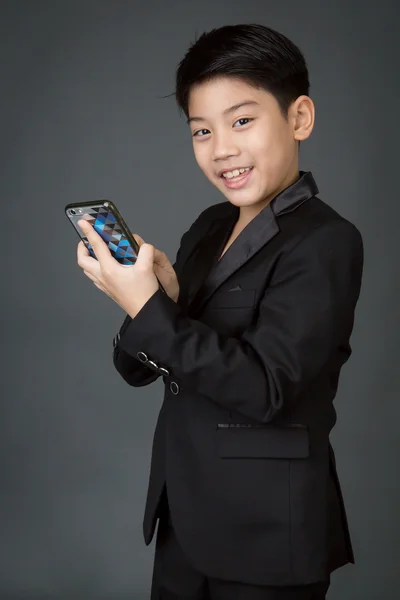 Feliz asiático niño en negro traje celebración digital celular —  Fotos de Stock