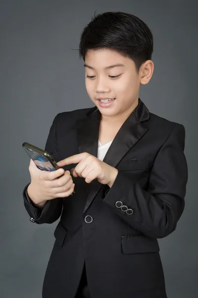 快乐的亚洲孩子，穿黑色西装，手持数字蜂窝电话 — 图库照片