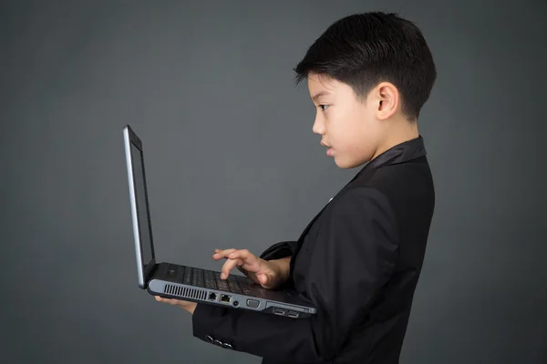 ノート パソコンで黒い服を着て少年アジア — ストック写真