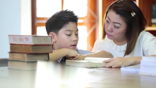 Lezen met leraar - een basisschool jongen wordt voorgelezen aan haar leraar — Stockvideo