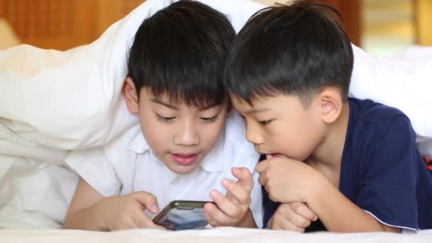 Asiático niño están jugando en la tableta, sonriendo, acostado en la cama . — Vídeo de stock