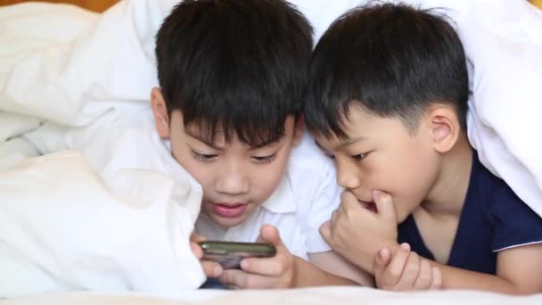 Asiático niño están jugando en la tableta, sonriendo, acostado en la cama . — Vídeo de stock