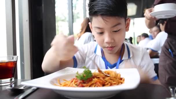 Little Asian boy eating spaghetti at restaurant with smile face — Stock Video