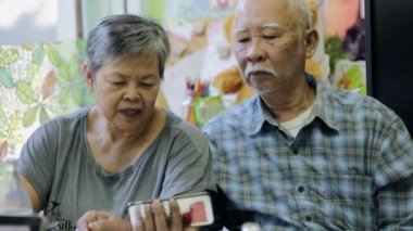 Mutlu asya yaşlı erkek ve kadın birlikte akıllı telefon kullanarak, gülümseme yüz ile .