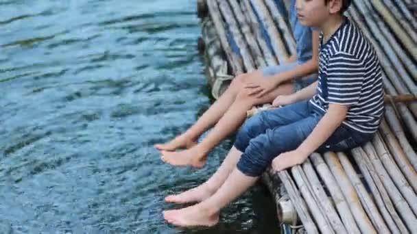 Jonge Aziatische broer en zus spelen water in bamboevlot — Stockvideo
