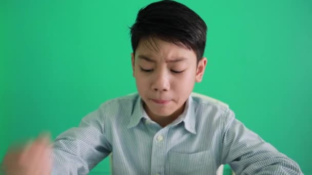 Mutlu Asyalı çocuk yeşil backgroud yüzünde bir gülümseme ile metin okuma — Stok video