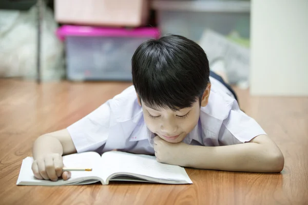 Asiático menino descansar no chão fazendo lição de casa — Fotografia de Stock