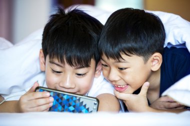 Asyalı okul öncesi çocuklar birlikte smartphone üzerinde oynama 