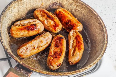 Yanmış tavada altı yanmış Alman sosisi.