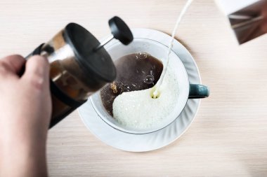 Süt ve sade kahve, yin-yang şeklinde bir fincanda karıştırılır.