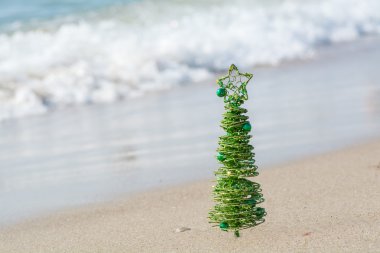 Kum deniz dalgaları zemin karşı parlayan yeşil dekoratif Noel ağacı