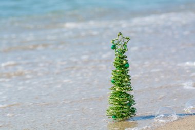 Kum deniz dalgaları zemin karşı parlayan yeşil dekoratif Noel ağacı