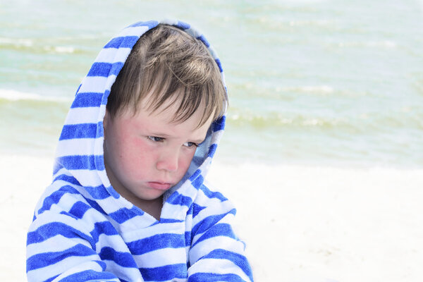Little cute kid hurt and pouted, disappointed. Beautiful little kid with atopic dermatitis on the background of the sea