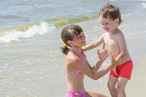 Sahilde büyük kız kardeşi bebek kardeşim ve dalgalar deniz zemin karşı sarılmak istiyor