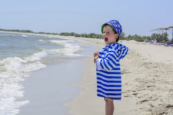 Menino com olhos azuis gritando de felicidade na praia, martelando — Fotografia de Stock