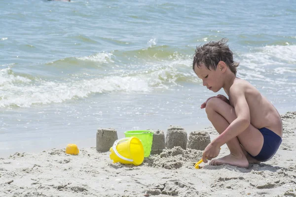 Chico jugando con arena en la playa, construyendo torres — Foto de Stock