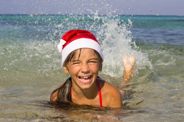 Petite fille dans le chapeau du Père Noël nage dans la mer — Photo