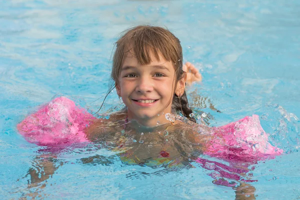 Chica en las mangas flota en la piscina — Foto de Stock