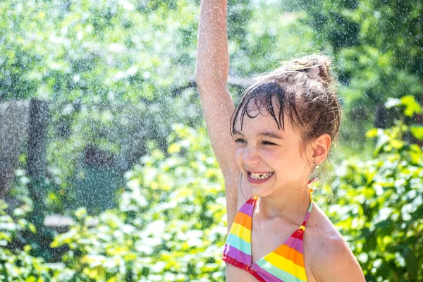 Hermosa niña en el spray de agua en el jardín — Foto de Stock