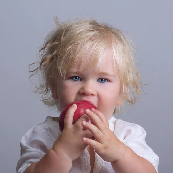 Bebê detém uma maçã vermelha comer — Fotografia de Stock
