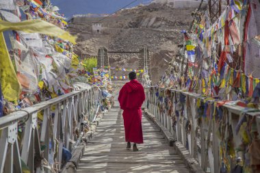 Bir keşiş tarafından renkli Tibet çevrili köprü yolu yürür